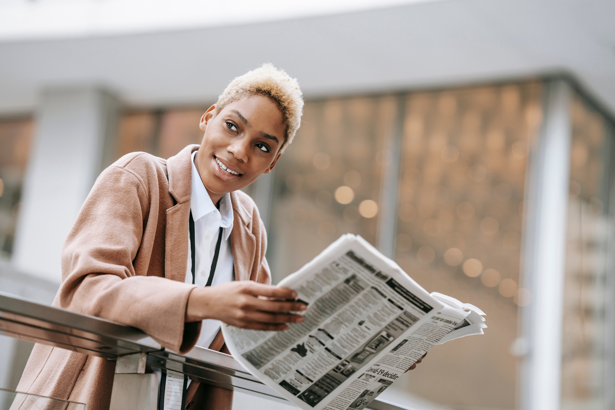 Cheerful ethnic businesswoman leaning on railing