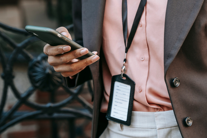 Faceless ethnic businesswoman using smartphone on street