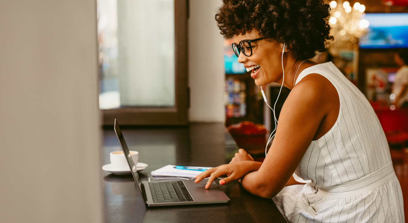 Smiling Woman Sitting at Cafe Using Laptop